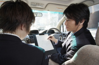 車内で調査内容を説明する探偵